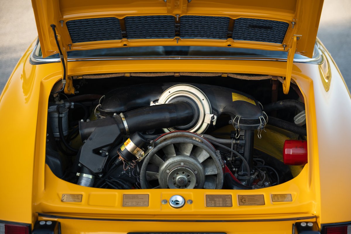 Yellow 1973 Porsche 911S Targa engine bay, showing air-cooled flat-six engine.