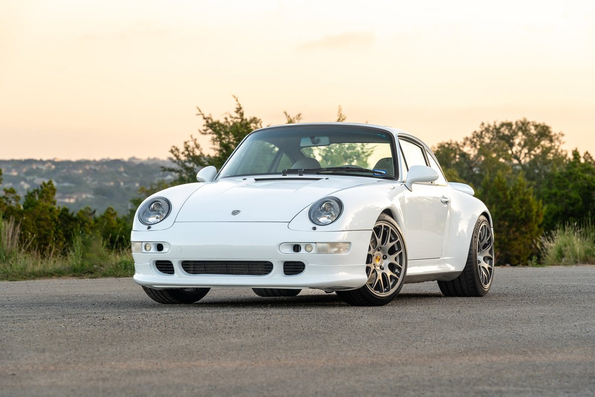 White 1997 Porsche 993 C4S with aftermarket rims, parked on asphalt road.