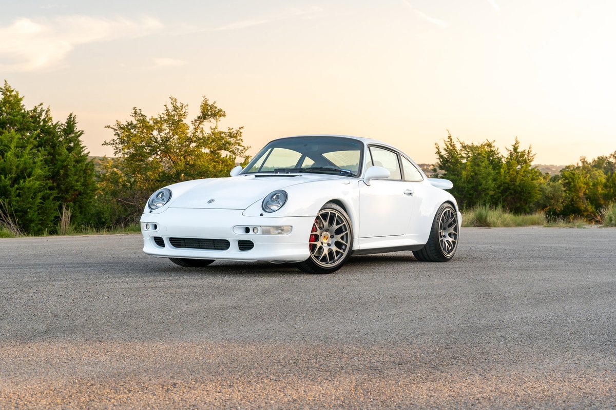1997 Porsche 993 C4S in Glacier White, featuring intricate alloy rims and red brake calipers.