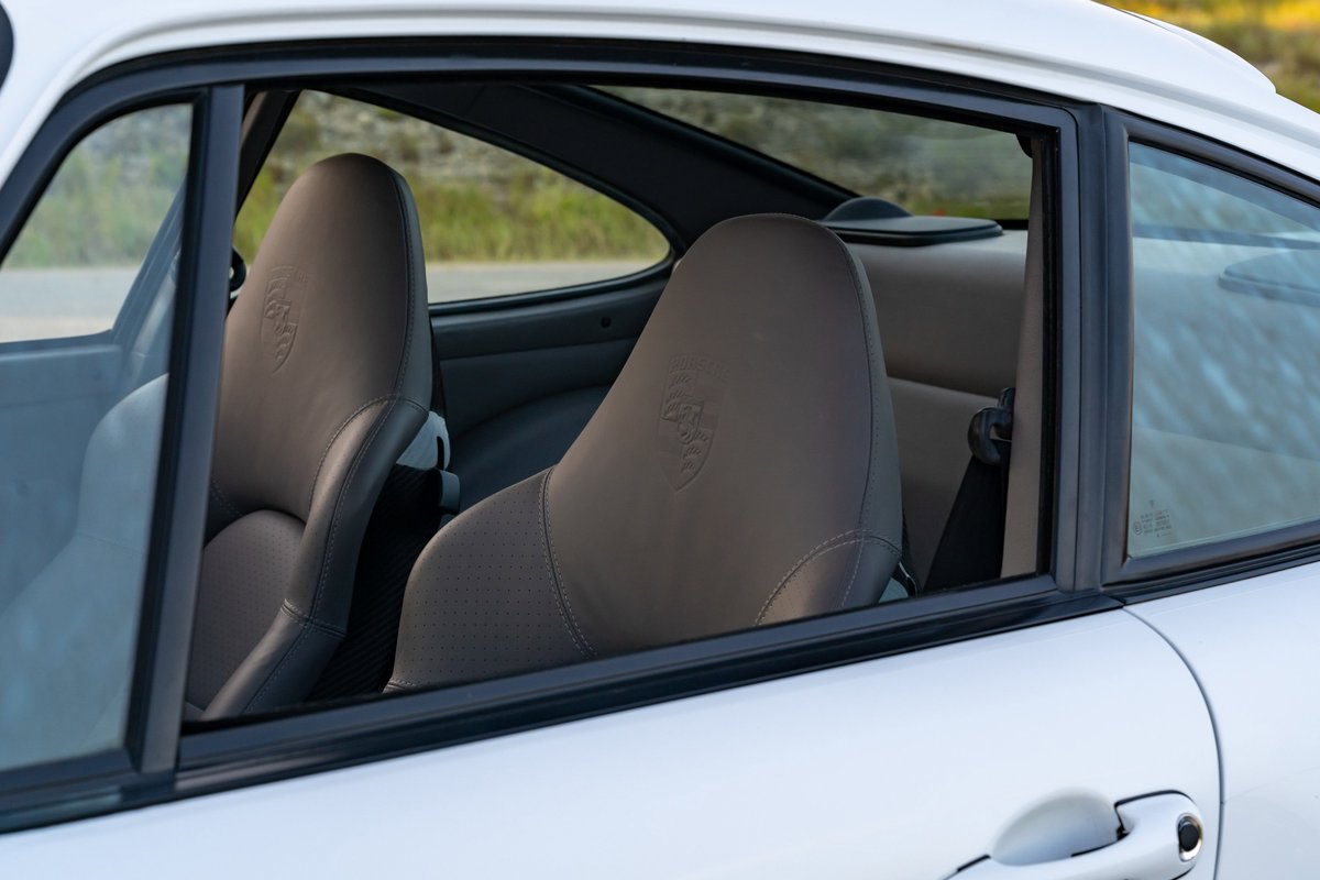 Interior view of a 1997 Glacier White Porsche 993 C4S showing tan leather seats with embossed crests.