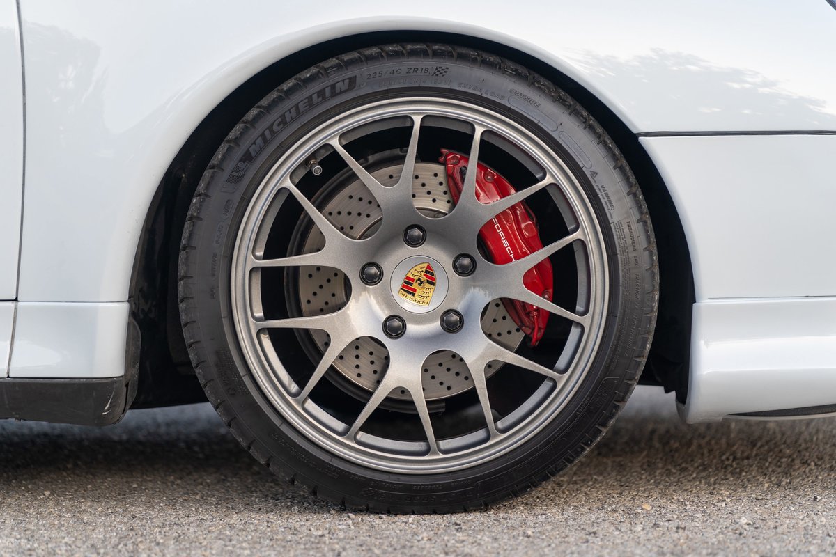 Close-up of a silver 1997 Porsche 911 (993) C4S wheel with red brake calipers.