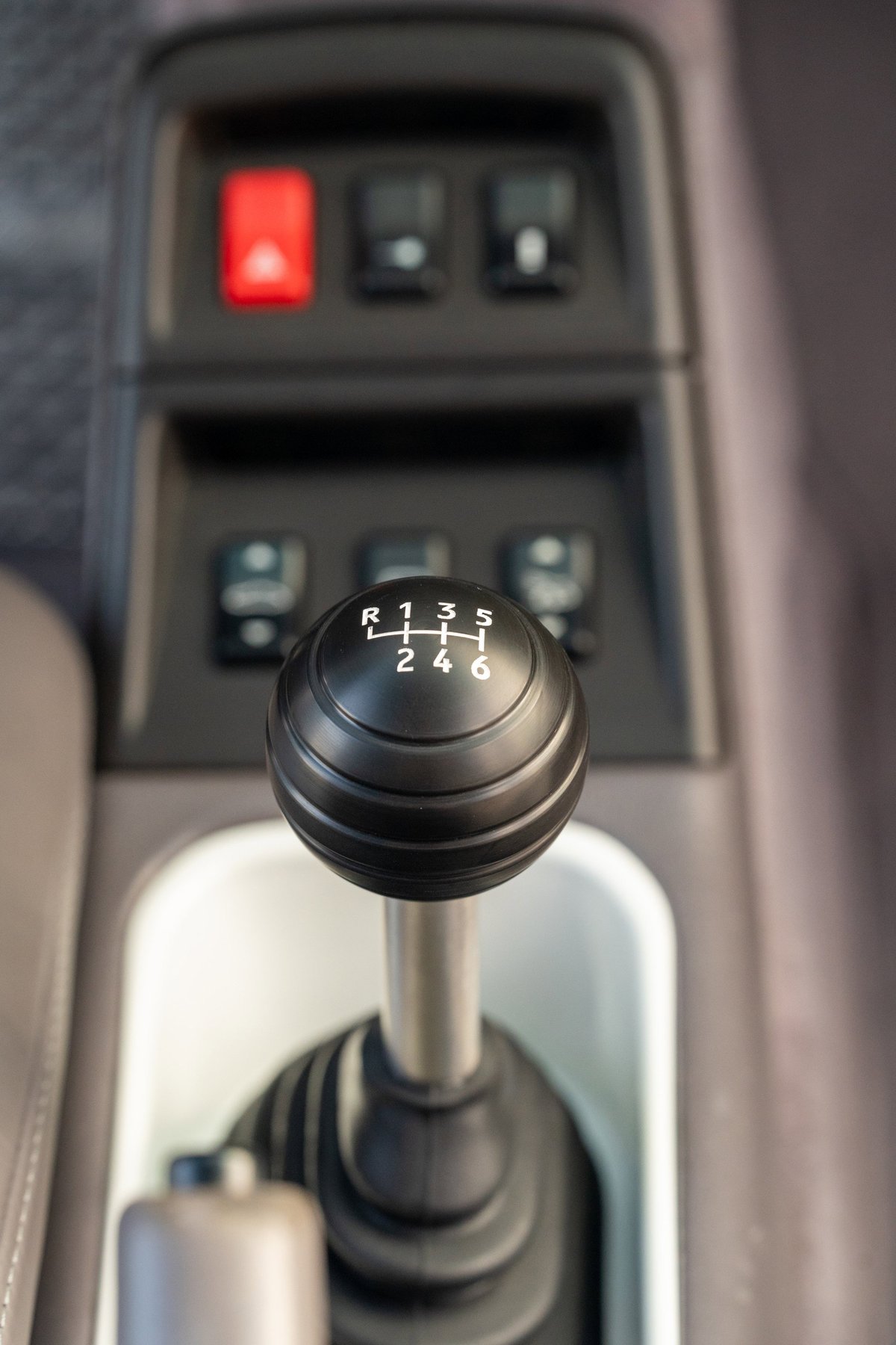1997 Porsche 993 C4S manual gear shift knob with 6-speed pattern and red hazard switch.