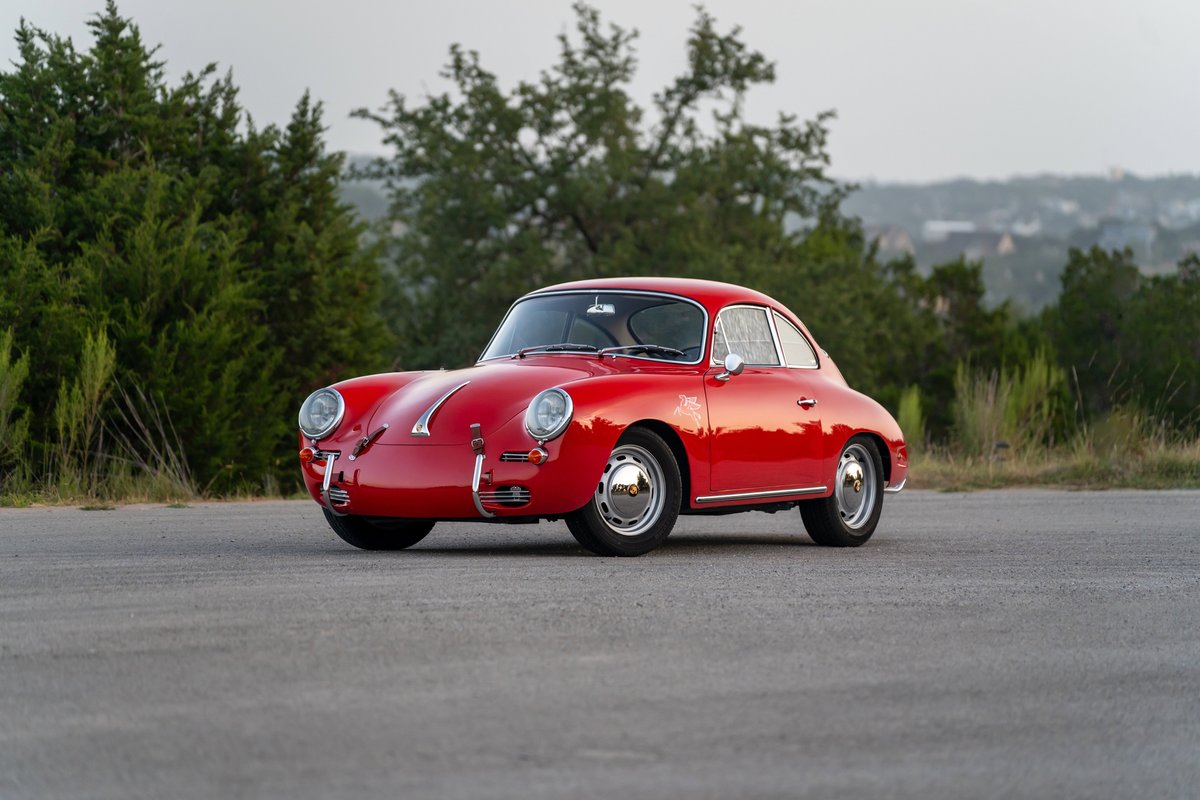 A red 1965 Porsche 356C with chrome hubcaps and side trim.