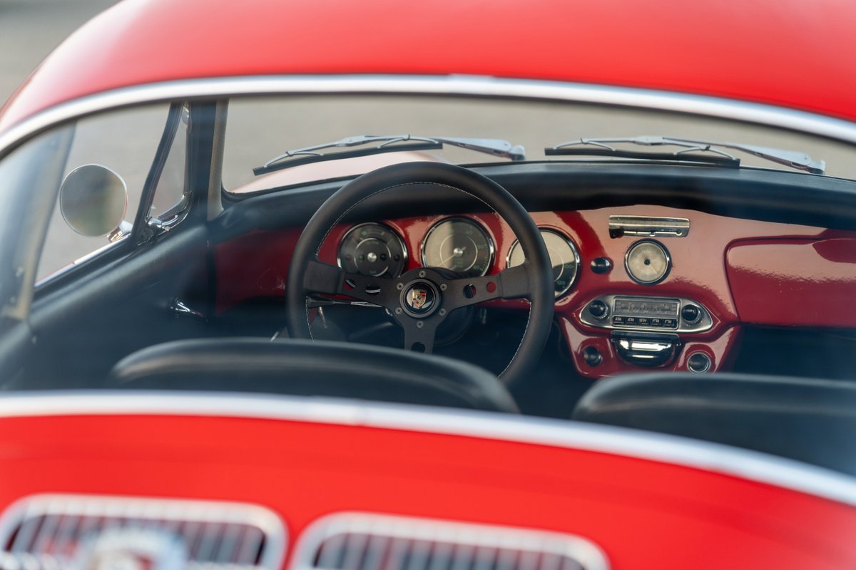 Red 1965 Porsche 356C interior with classic steering wheel and dashboard.
