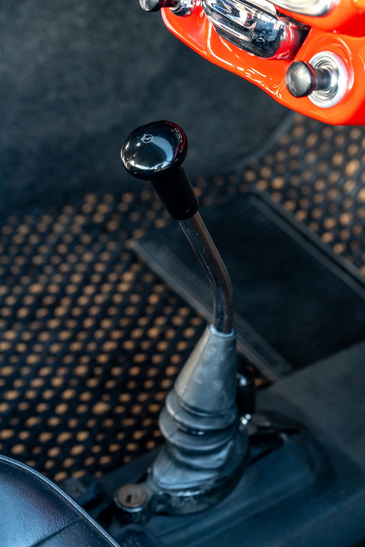 Close-up of the black gear shifter on the Signal Red 1965 Porsche 356C dashboard.