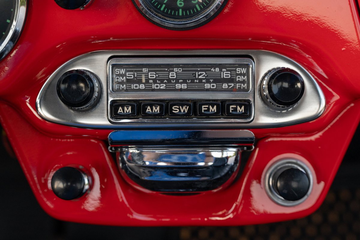 1965 Porsche 356C Signal Red Blaupunkt radio console with chrome trim and black knobs.