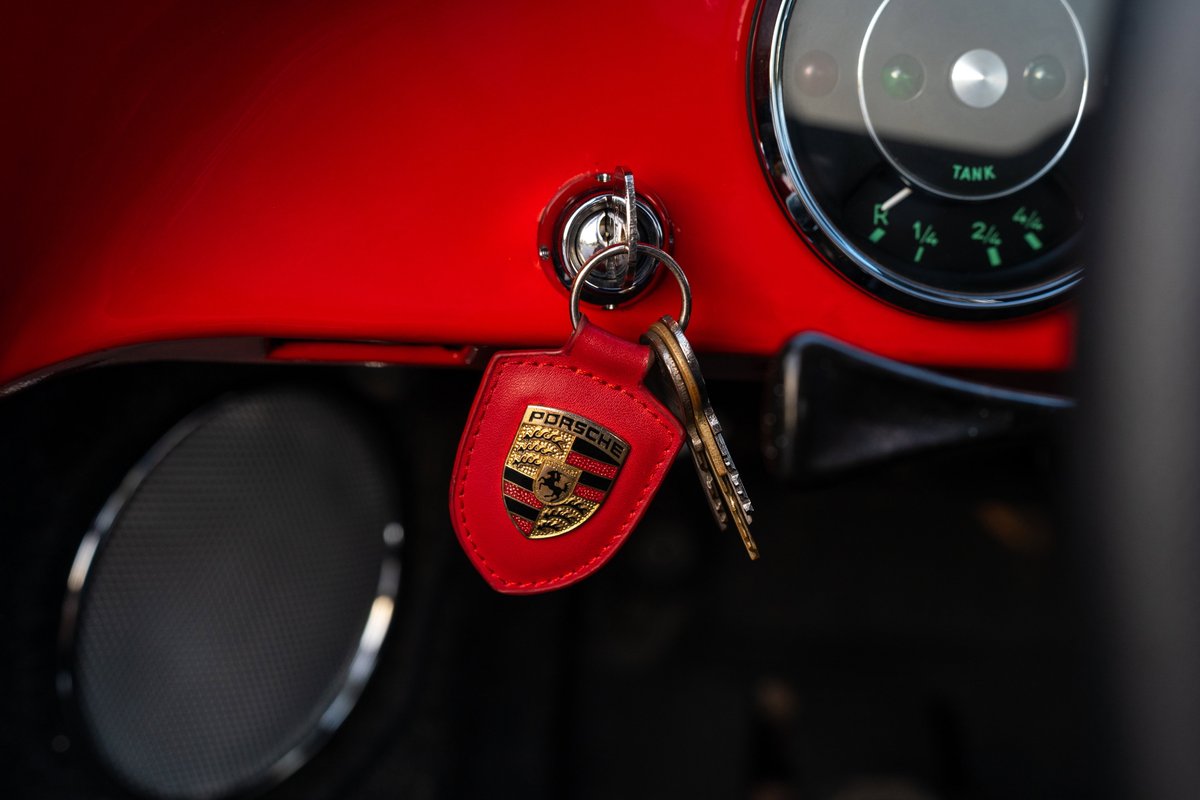 Close-up of ignition and key fob with Porsche crest in a red 1965 Porsche 356C interior.