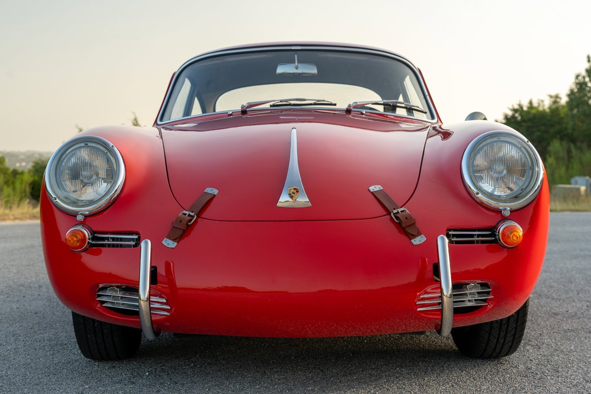 Front view of a red 1965 Porsche 356C with leather hood straps and chrome trim.