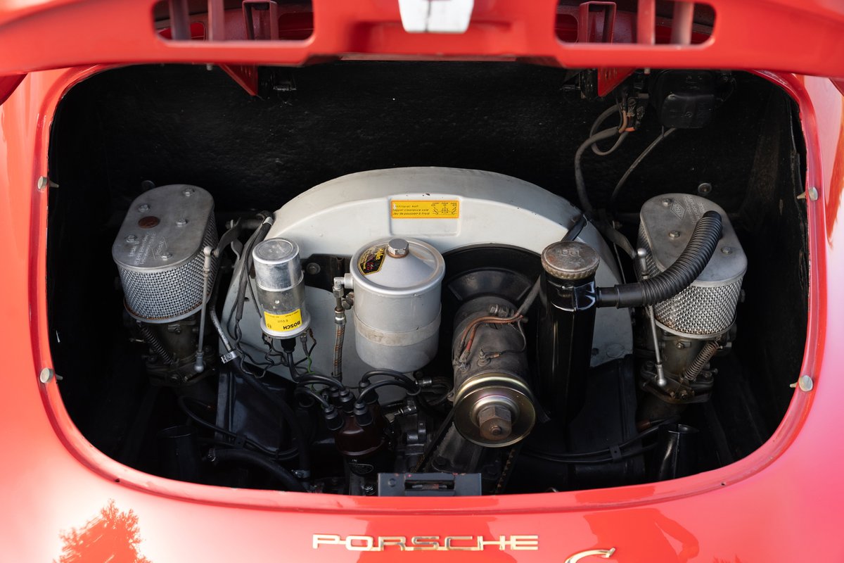 Vintage Porsche 356C engine bay, featuring dual carburetors and air filters. Red exterior trim.