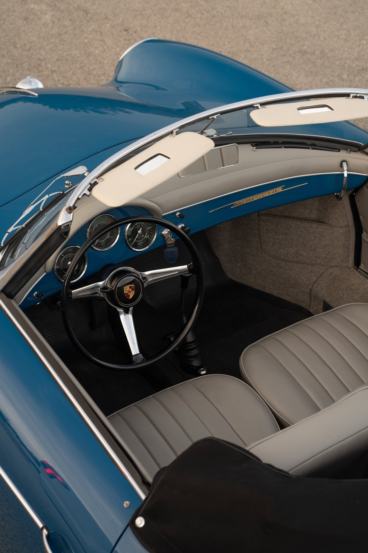 Interior shot of a royal blue 1960 Porsche 356B Roadster. Features tan visors, grey seats & dashboard trim.