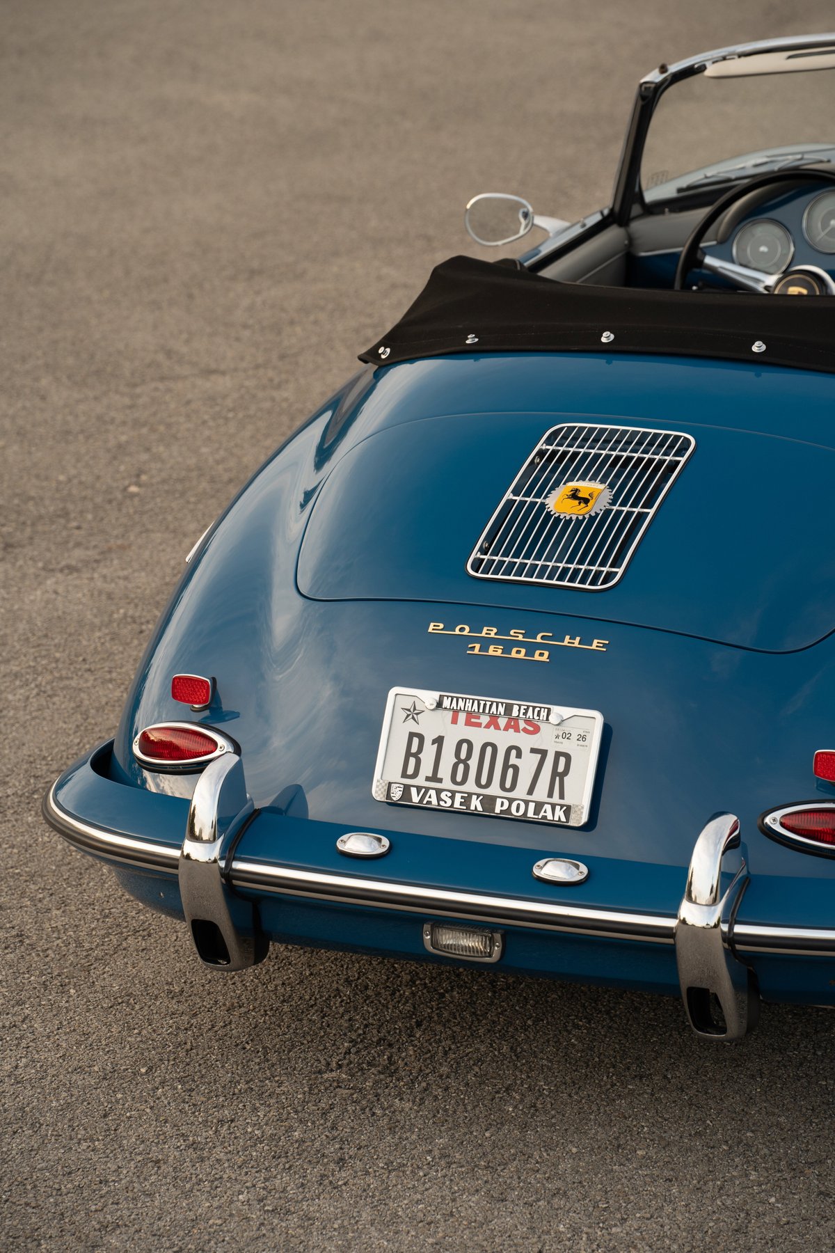 Rear view of a Royal Blue 1960 Porsche 356B Roadster with chrome bumpers and a yellow Porsche badge.