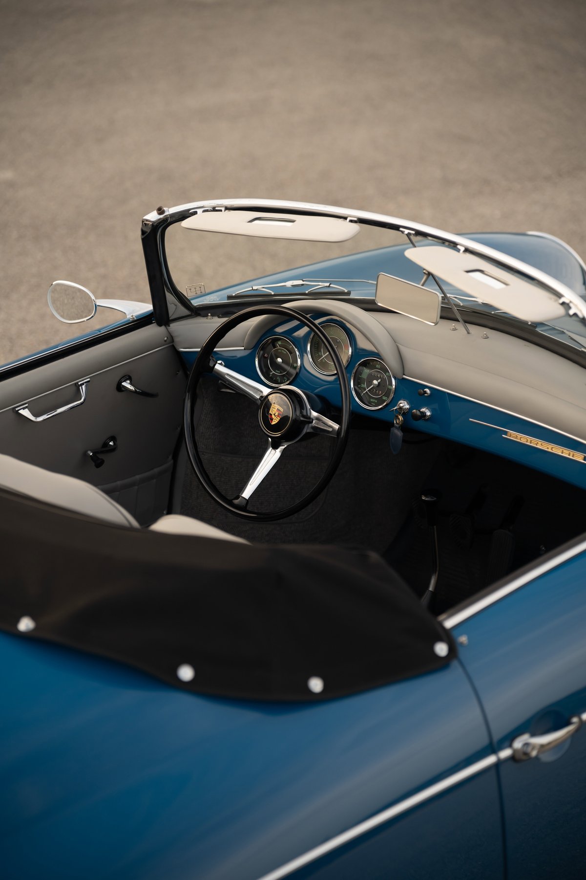 Interior of a royal blue 1960 Porsche 356B Roadster, featuring a classic steering wheel and dashboard.