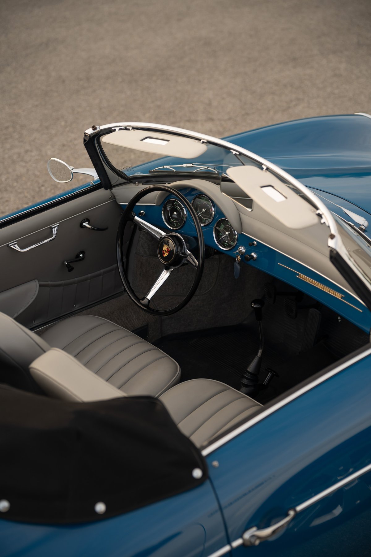 Interior view of a royal blue 1960 Porsche 356B Roadster, featuring classic gauges and grey leather seats.