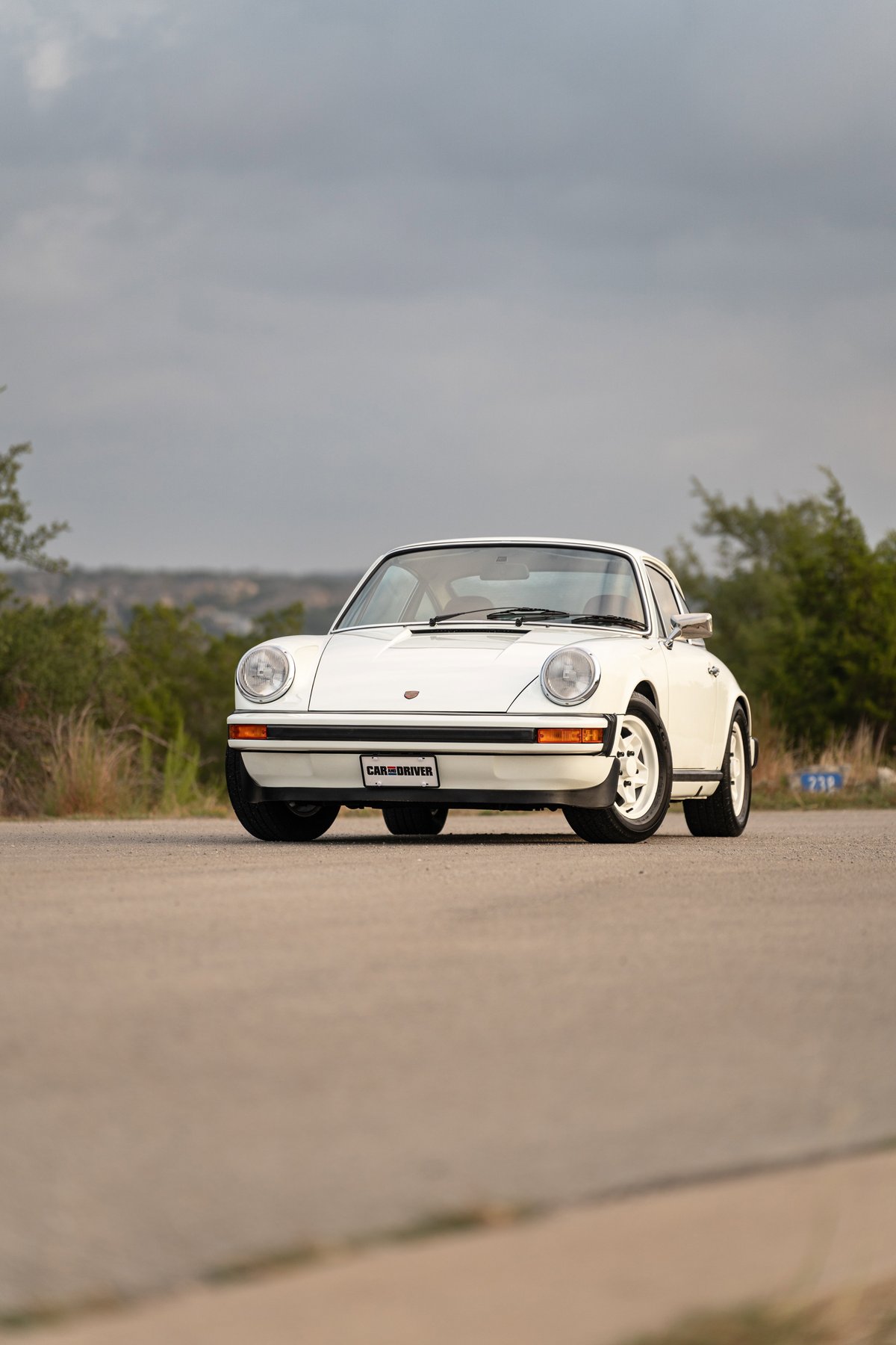 A white 1974 Porsche 911 coupe with chrome trim and turbines rims.
