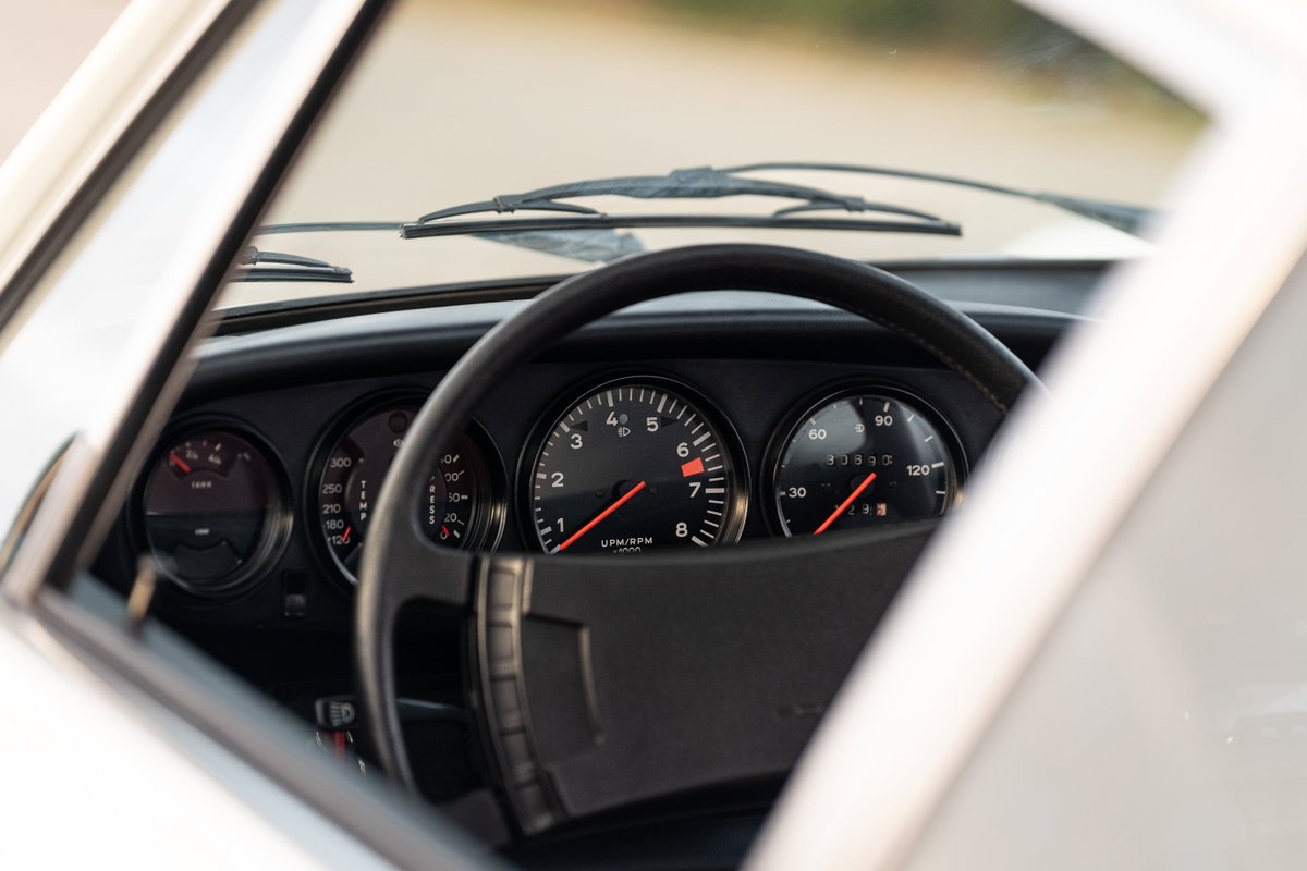 Interior shot of a 1974 Porsche 911 Coupe's dashboard, showing gauges and steering wheel.