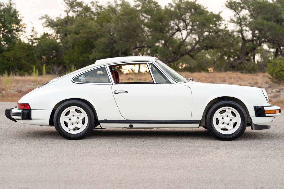 White 1974 Porsche 911 coupe with Fuchs-style rims and black trim.
