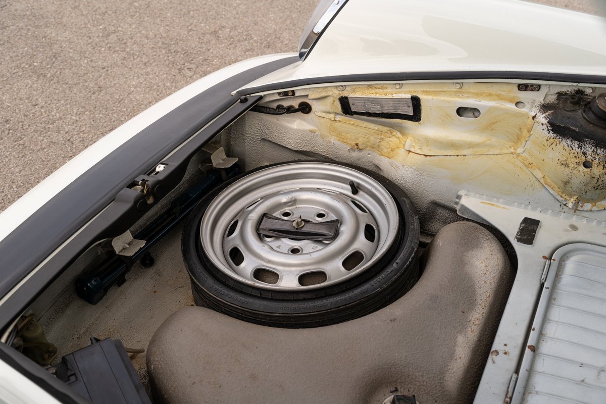 1974 Porsche 911 Coupe front trunk with spare tire, jack, and VIN plate.