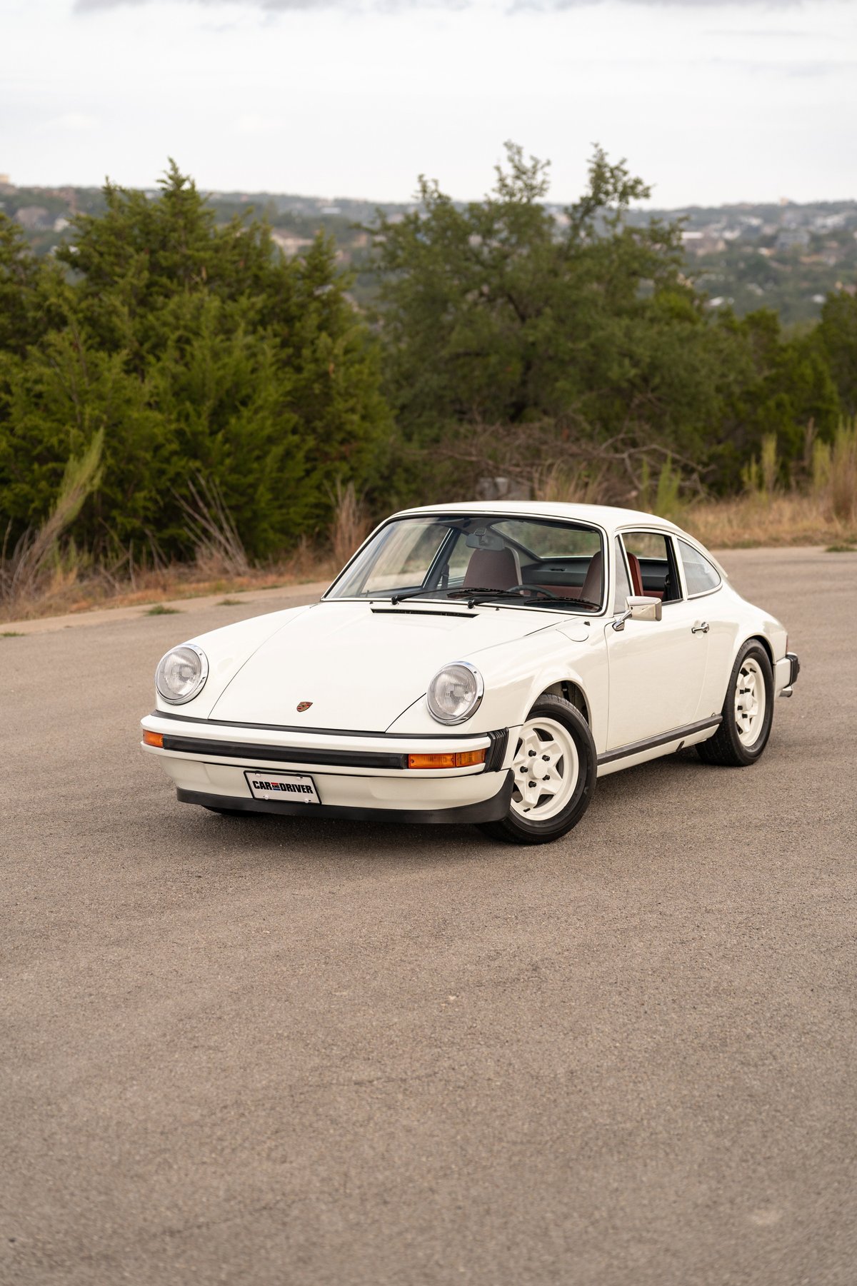 A white 1974 Porsche 911 coupe with black trim and classic five-spoke rims.