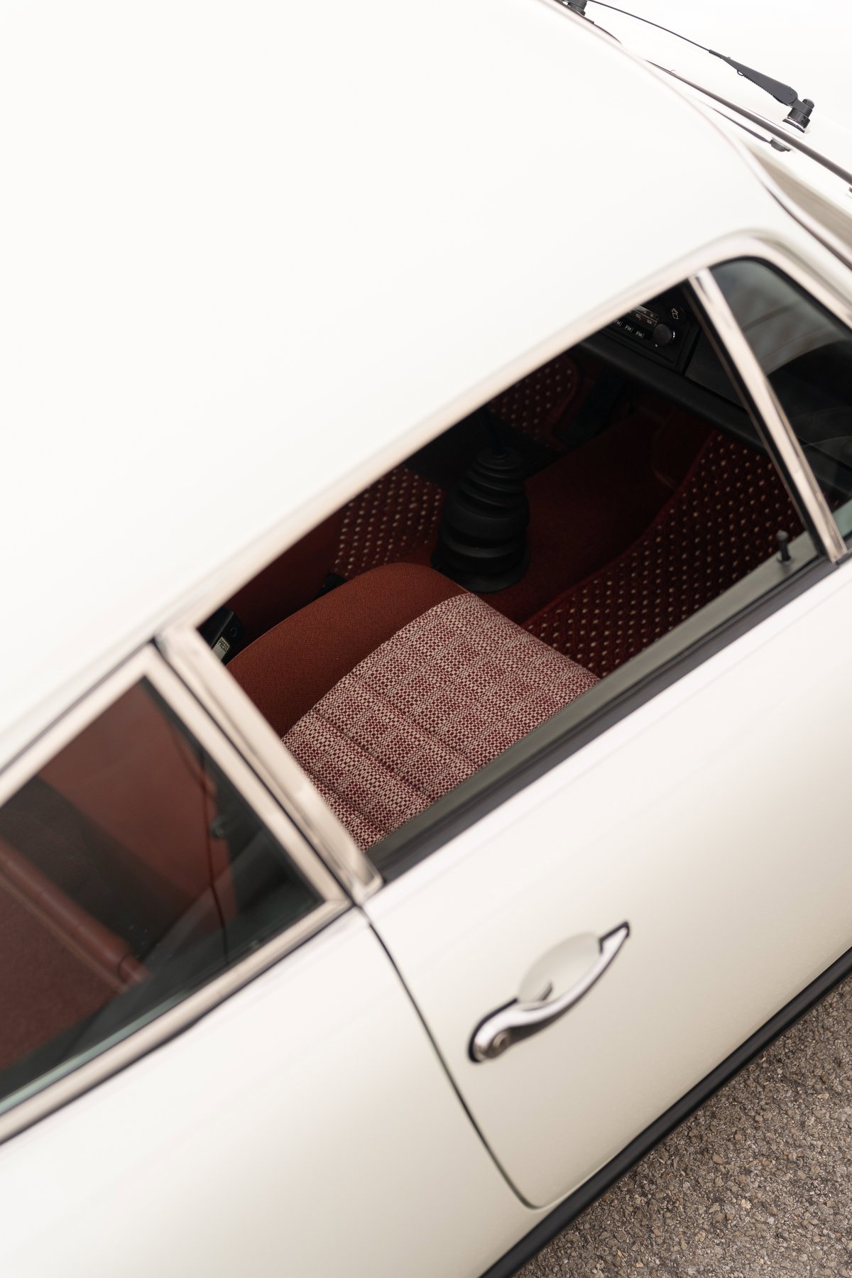1974 Porsche 911 coupe interior with plaid fabric seats and black shift knob.