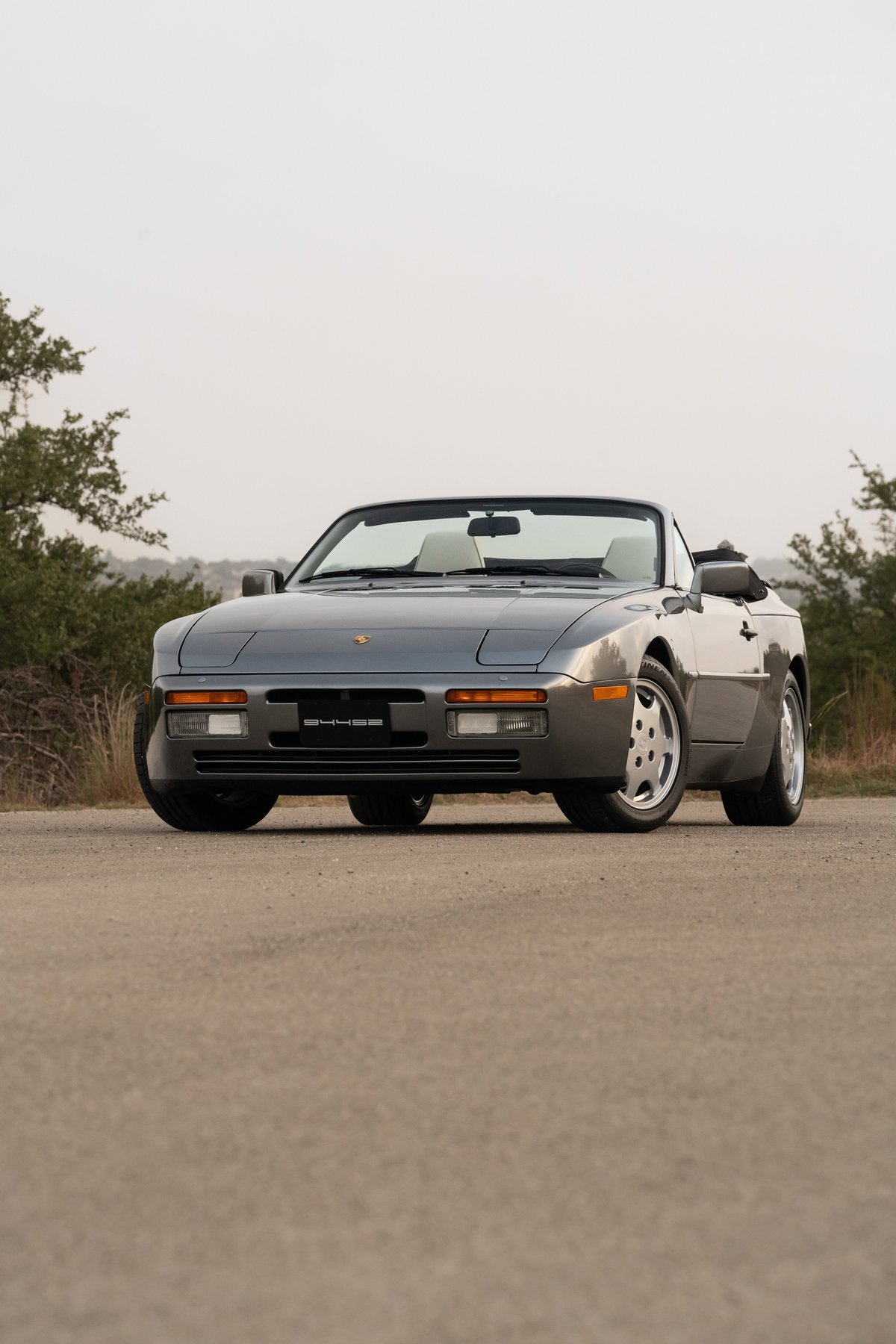A grey 1990 Porsche 944 S2 Cabriolet convertible with silver alloy rims and black trim.
