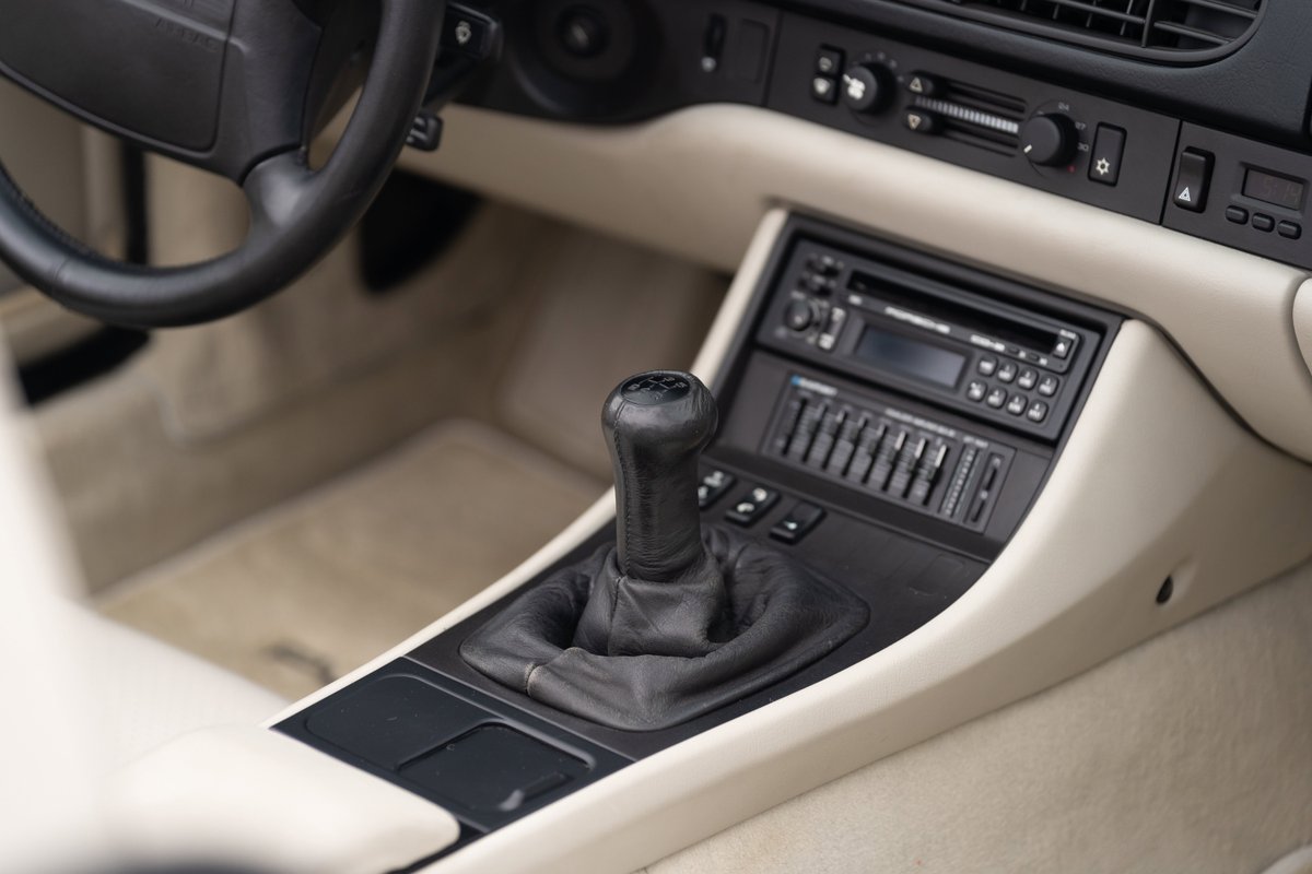 1990 Porsche 944 S2 Cabriolet interior, featuring a manual shifter, beige trim, and an aftermarket stereo.
