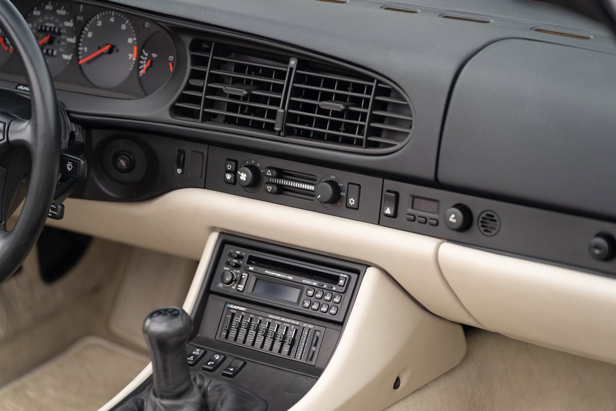 1990 Porsche 944 S2 Cabriolet interior, titanium metallic dash trim, beige upholstery, black steering wheel, five-speed manual.