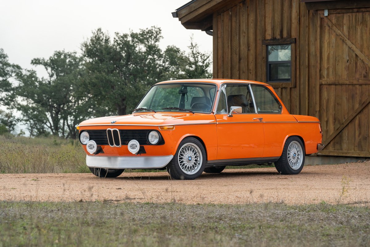 Inka Orange 1976 BMW 2002 with period-correct rally wheels and Hella lights.