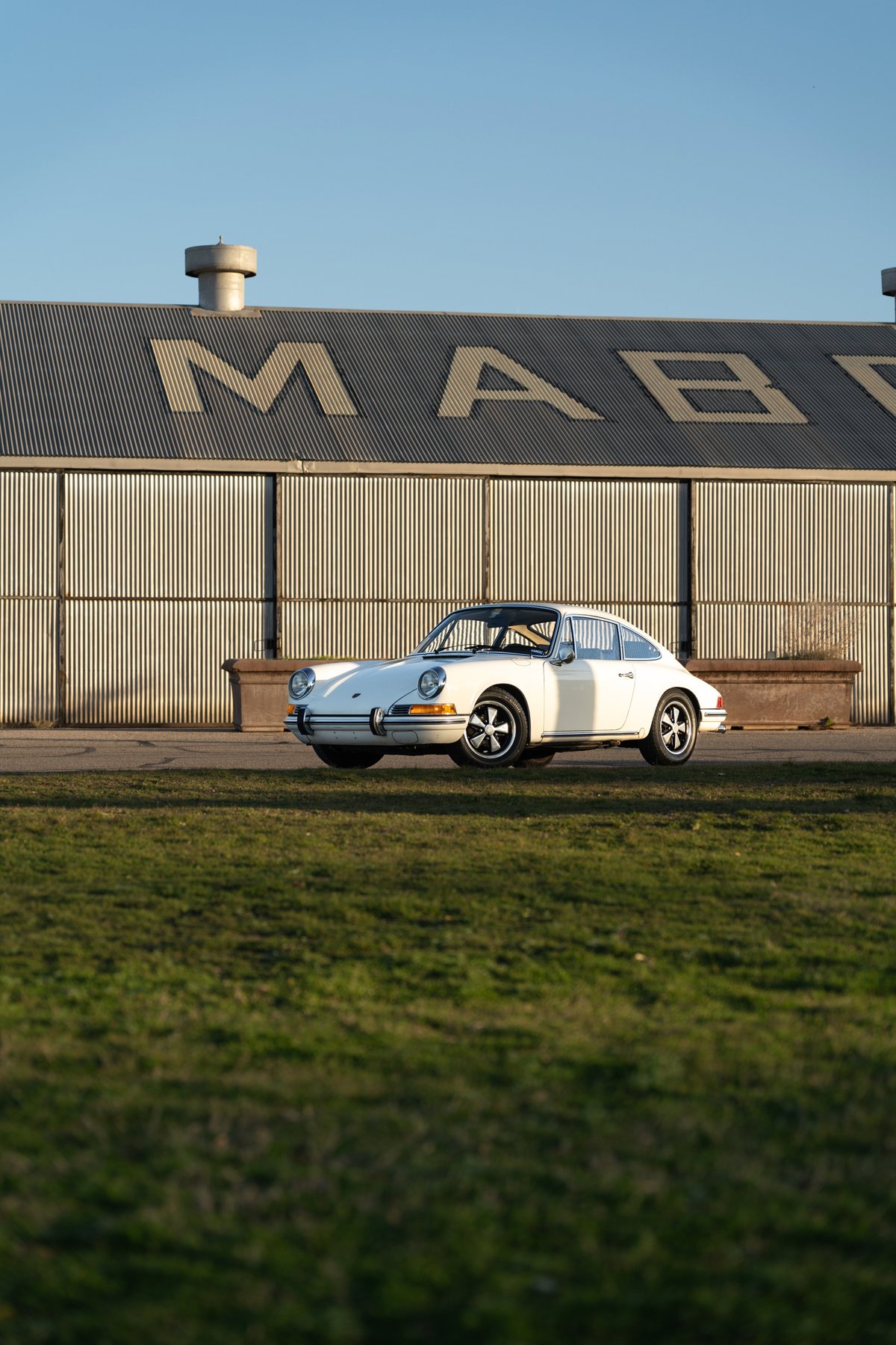 A white 1970 Porsche 911T coupe with chrome trim and Fuchs wheels.