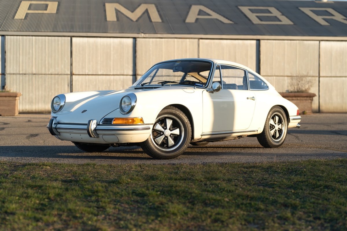 A white 1970 Porsche 911 T coupe with chrome trim and Fuchs rims.