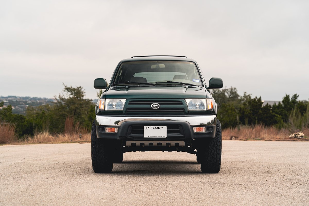 Front view of a dark green 2000 Toyota 4Runner with chrome trim and black rims.