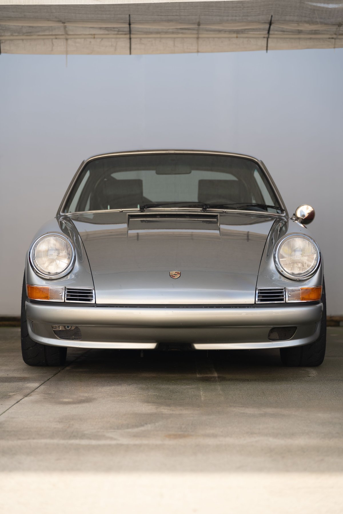 Silver Porsche 911 with chrome trim and round headlights.