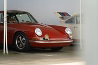 Red 1970s Porsche 911 with Fuchs wheels parked next to a Martini livery car.