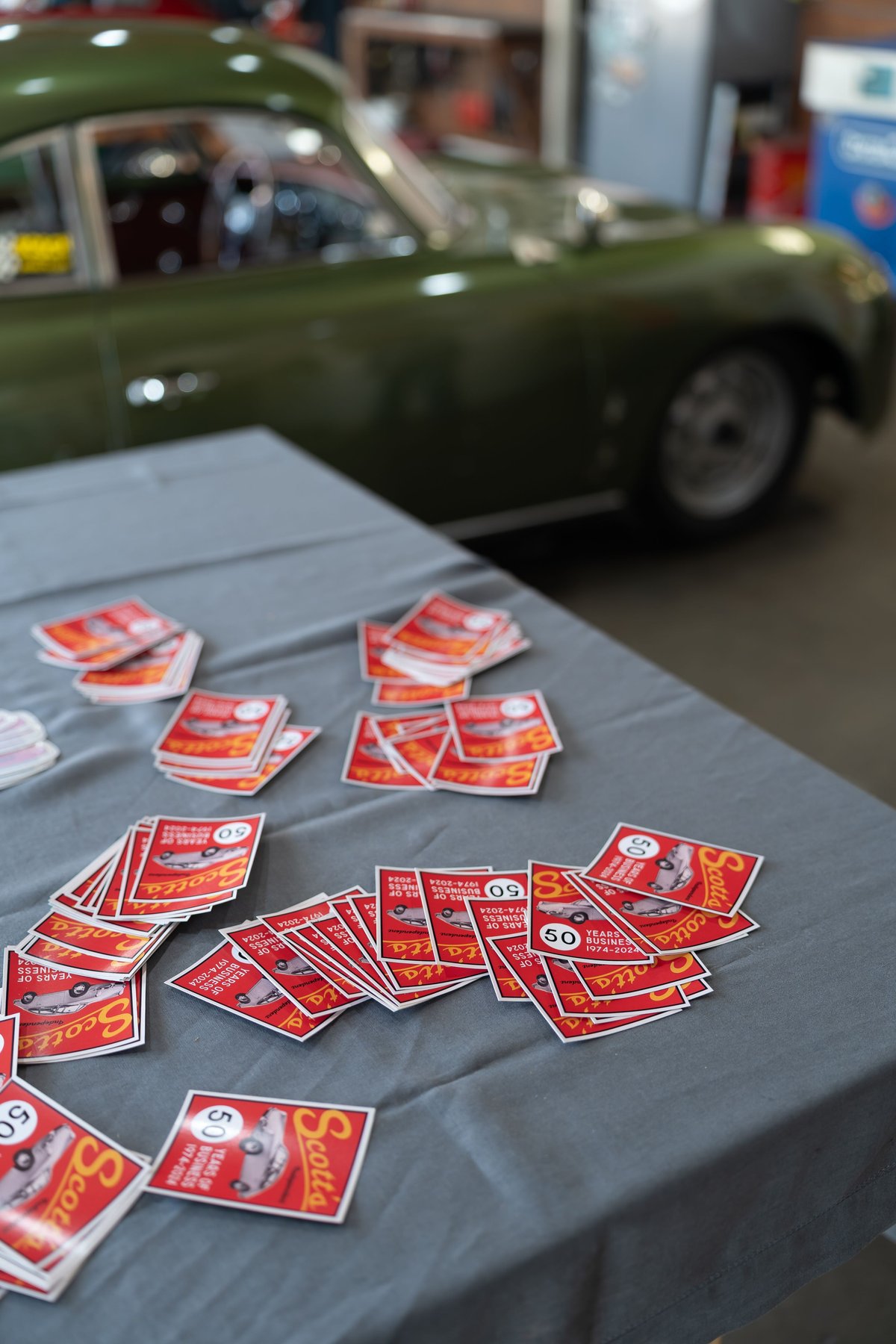 Green Porsche 356 with red "Scotts 50 Years" stickers and a polished rim.