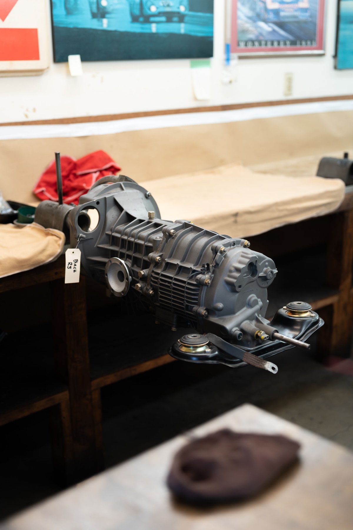 Porsche 911 gearbox on workbench, gray housing, metal trim.