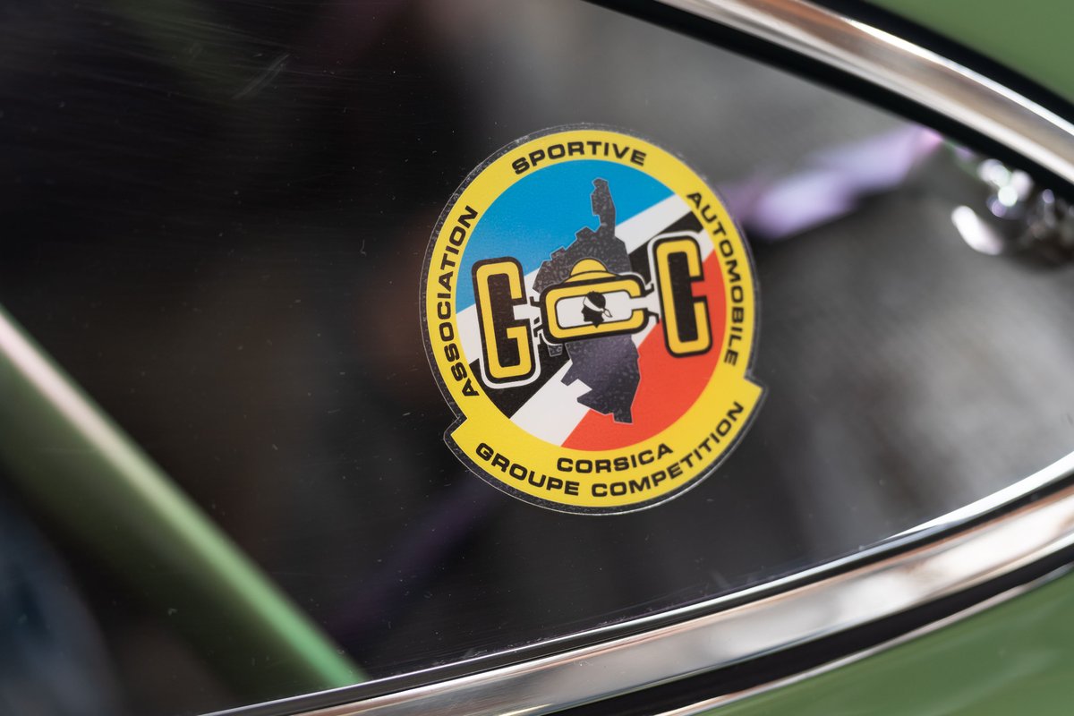 Close up on a Corsica Groupe Competition sticker on a green car's windshield.