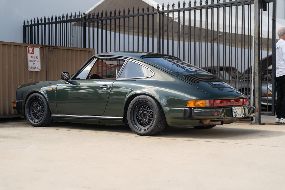 Dark green 1974-1989 Porsche 911 Carrera with black mesh rims.