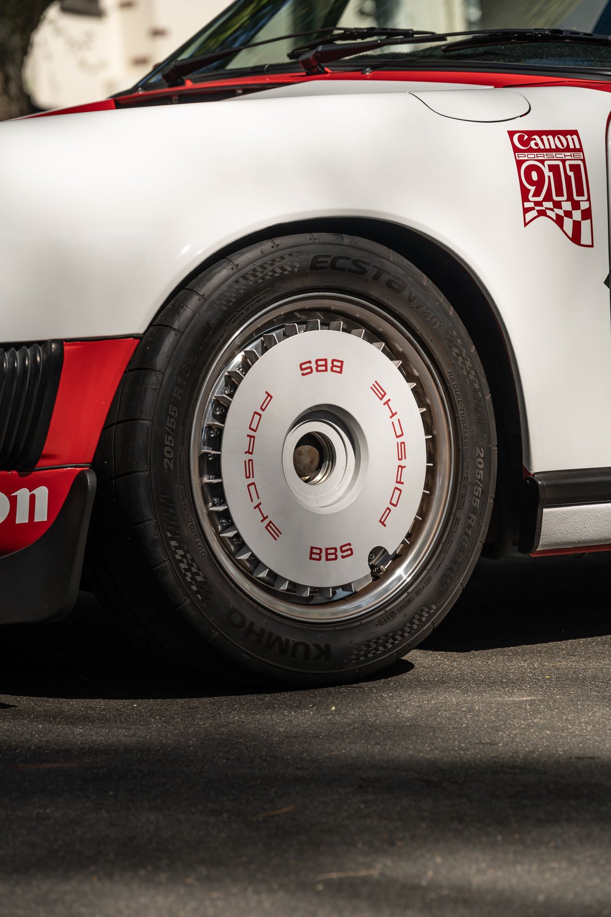 White Porsche 911 with red livery and BBS rims, featuring Canon graphics.
