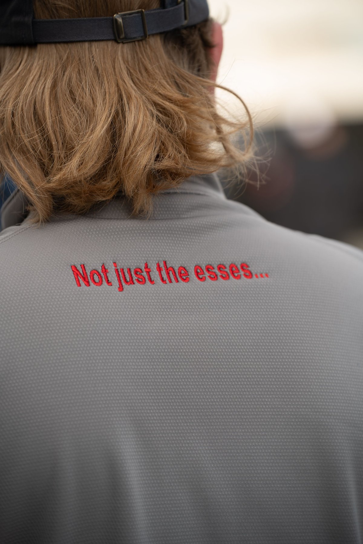 Close-up of a person's back wearing a gray shirt with red text. No car is visible.