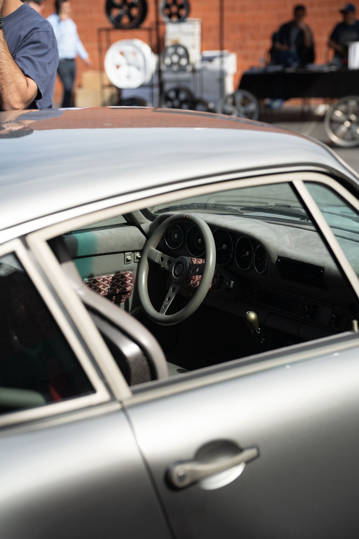Silver Porsche 911 interior with custom steering wheel and patterned trim.