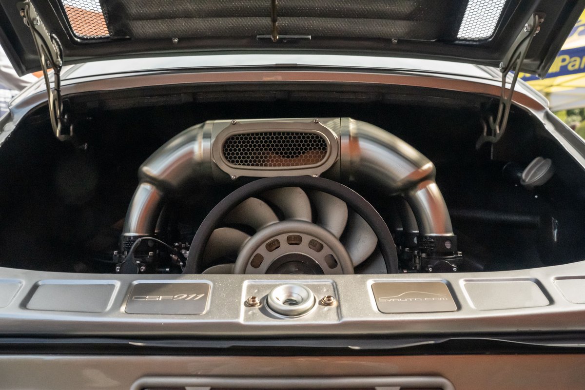 Silver Porsche 911 engine bay with custom exhaust and fan.
