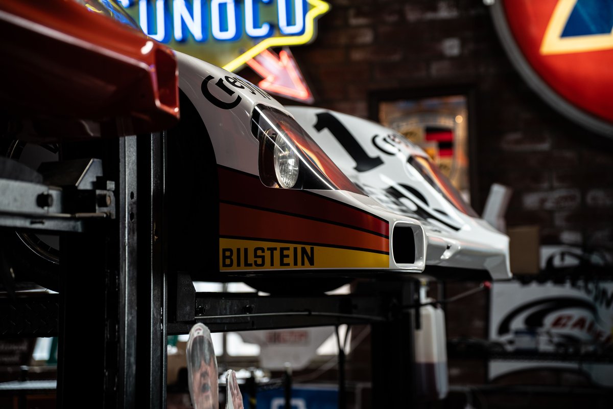 White and red 1970s-era race car with Bilstein livery, number 1, on a lift.