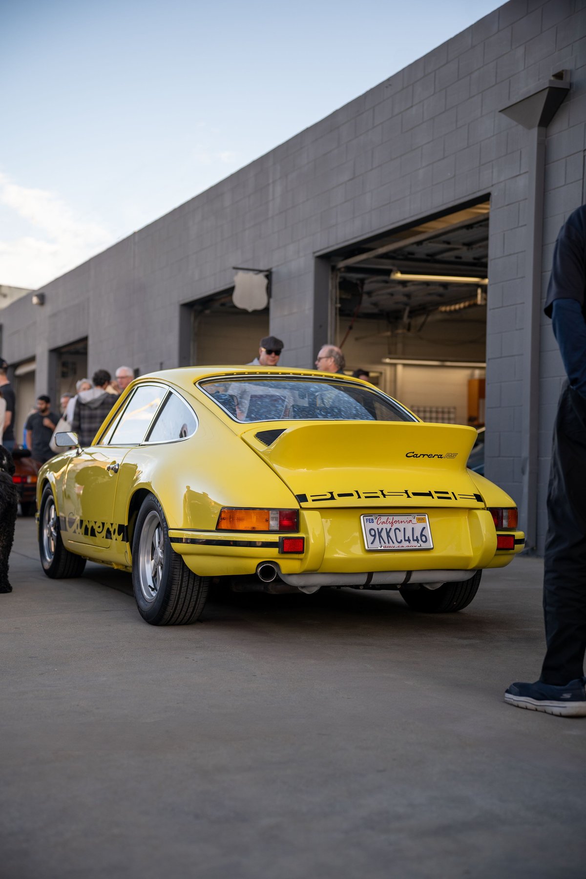 Yellow Porsche 911 Carrera RS with black livery and Fuchs rims.