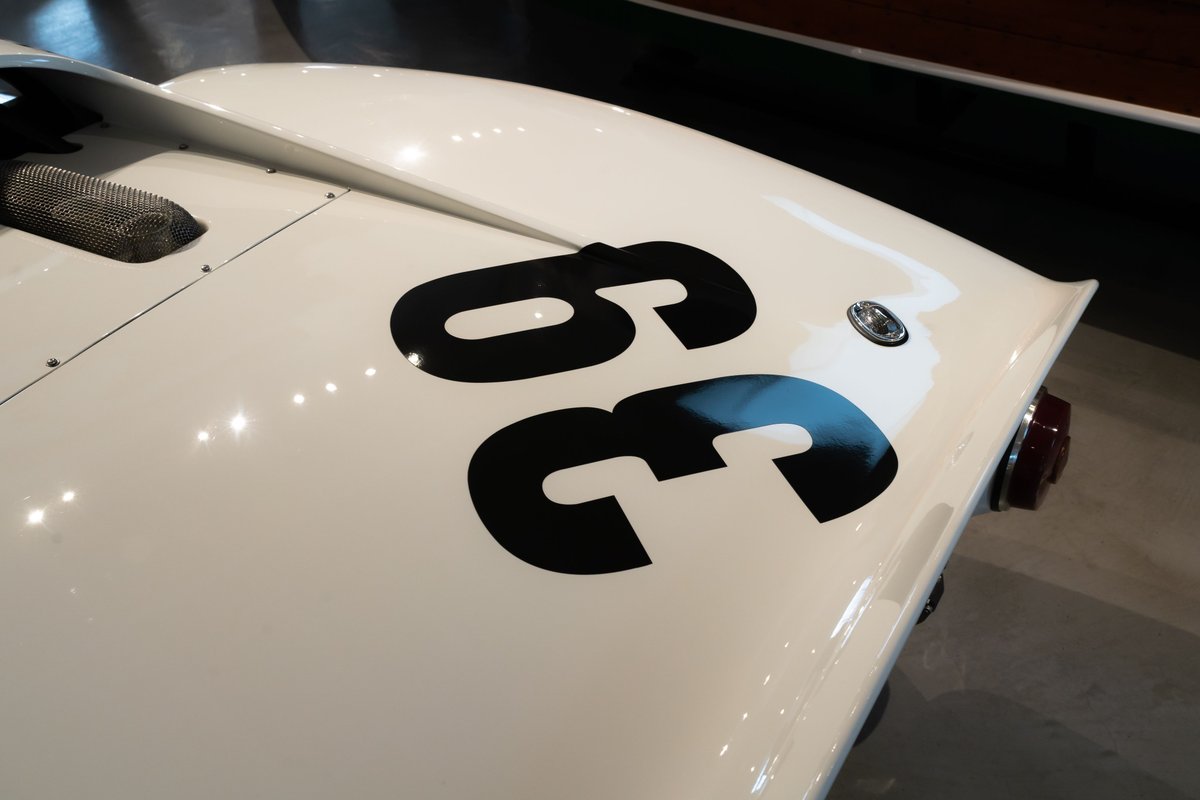 White classic race car with black "36" livery and chrome trim details at a car show.