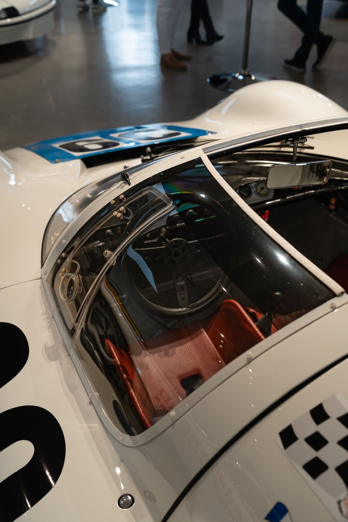 Close-up of a white 1970s race car's cockpit with blue #6 race livery and red seats.