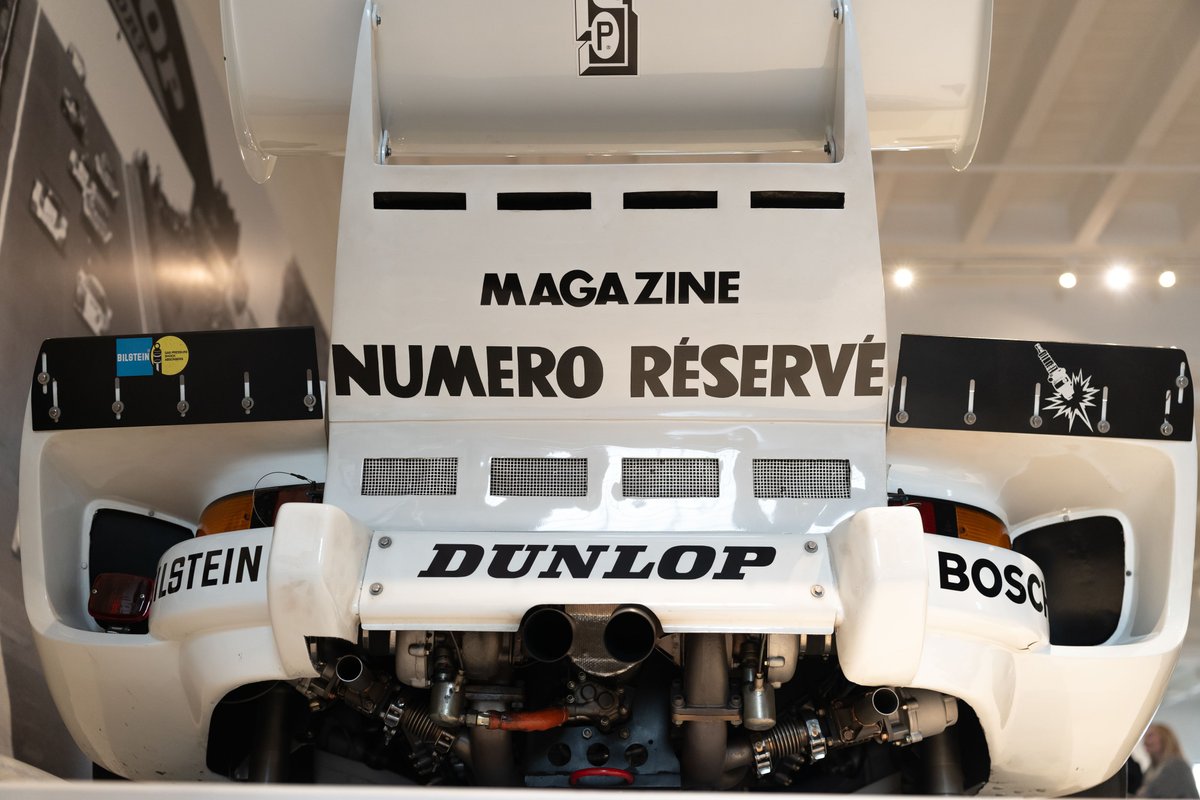 Rear view of a white Porsche race car with Dunlop tires and sponsor livery at the LIT Show LA.