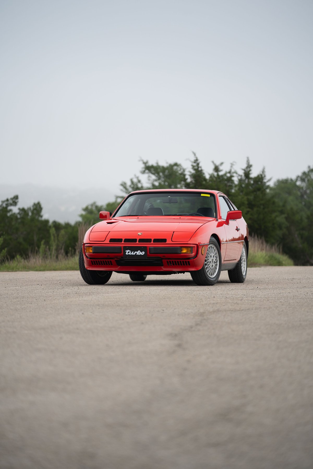 Red 1981 Porsche 924 Turbo with "Turbo" badge, classic turbine rims, and front intake trim.