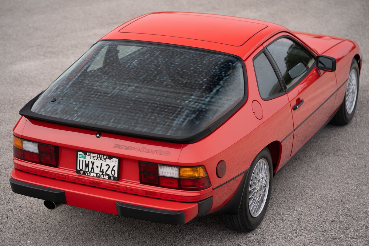 Red 1981 Porsche 924 Turbo rear-view showing spoiler, mesh rear window, and wire-spoke rims.