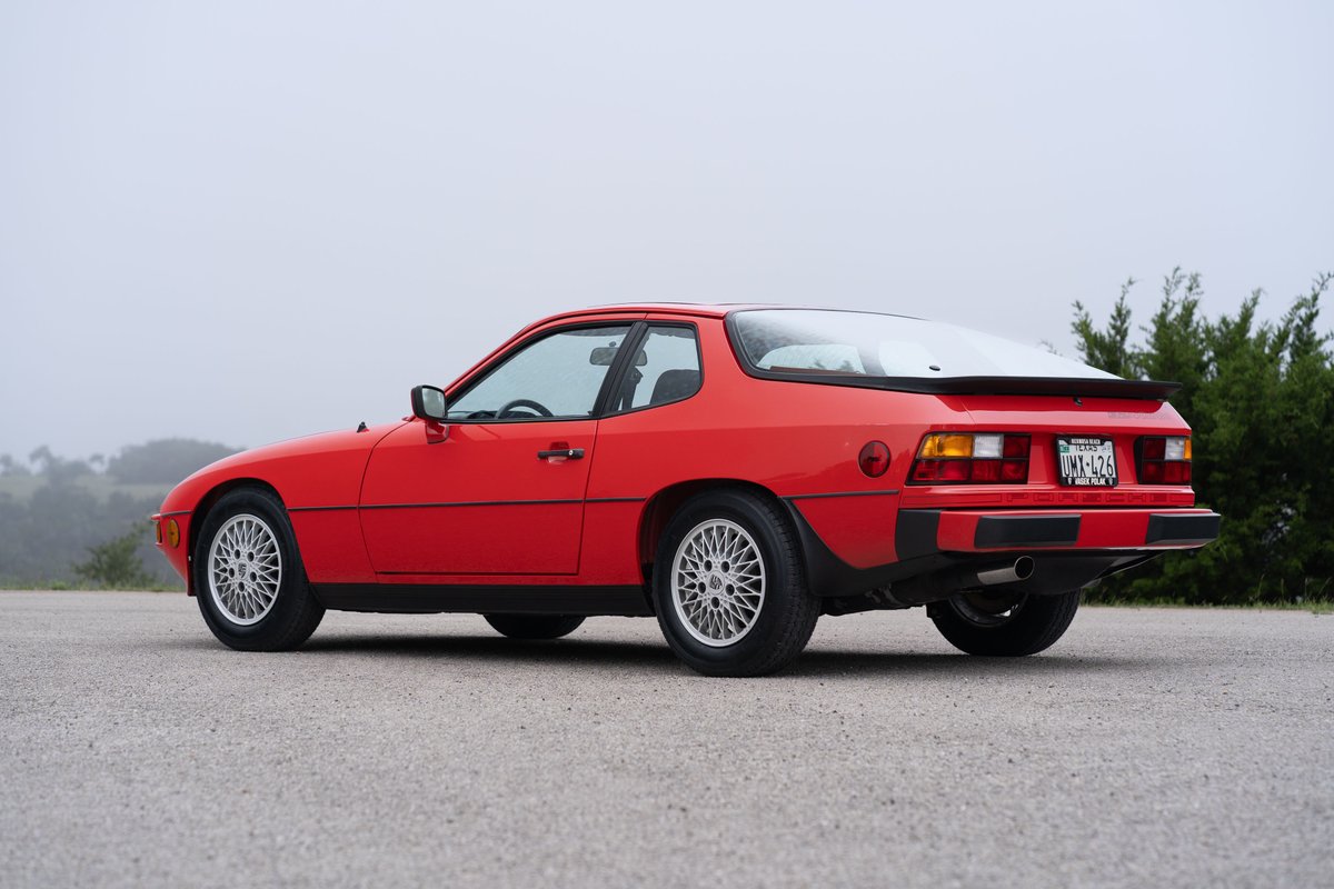 A Guards Red 1981 Porsche 924 Turbo coupe, rear quarter view, with silver alloy rims and black trim.