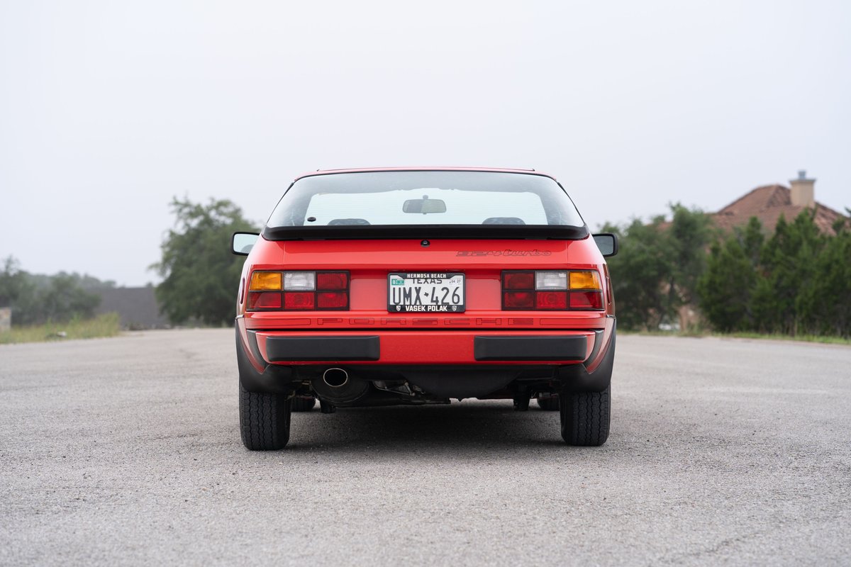 Red 1981 Porsche 924 Turbo from behind, with a spoiler and stock trim.