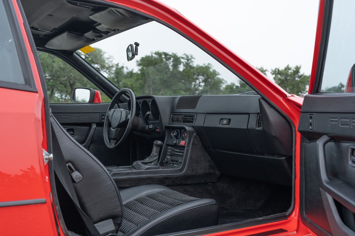 Interior view of a red 1981 Porsche 924 Turbo, showing black seats, dashboard, and door trim.